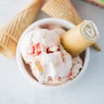 Strawberry Shortcake Ice cream in bowl with a roll and cones around the bowl