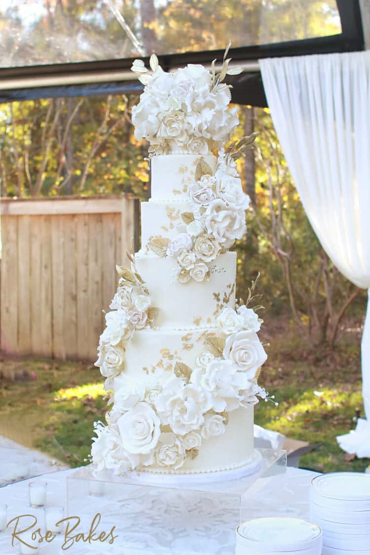 Cascading flowers on a white and gold wedding cake with gold leaf and gum paste roses, tulips, peonies and more.