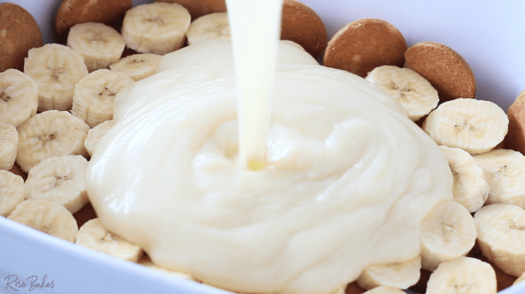 pudding mixture being poured over banana and cookie layers 
